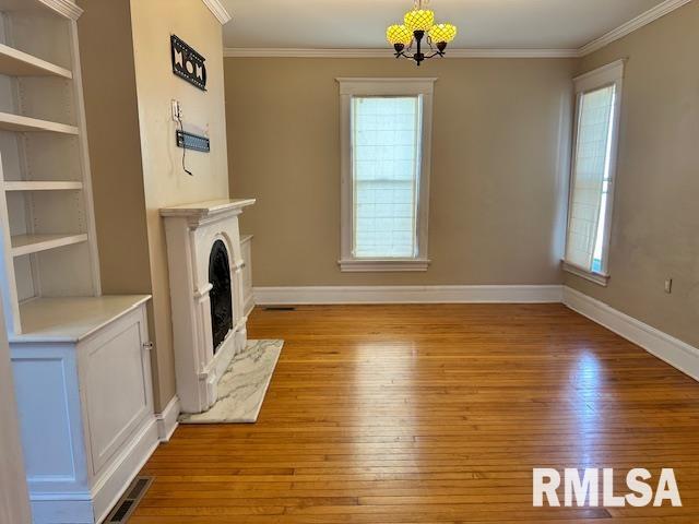 unfurnished living room featuring visible vents, an inviting chandelier, crown molding, and hardwood / wood-style flooring