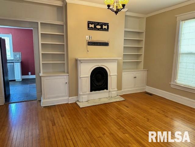 unfurnished living room with built in shelves, baseboards, hardwood / wood-style floors, and crown molding