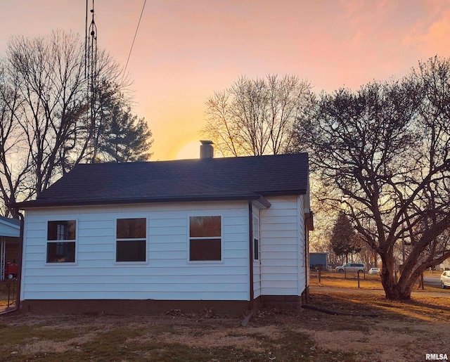 exterior space with a chimney and a shingled roof