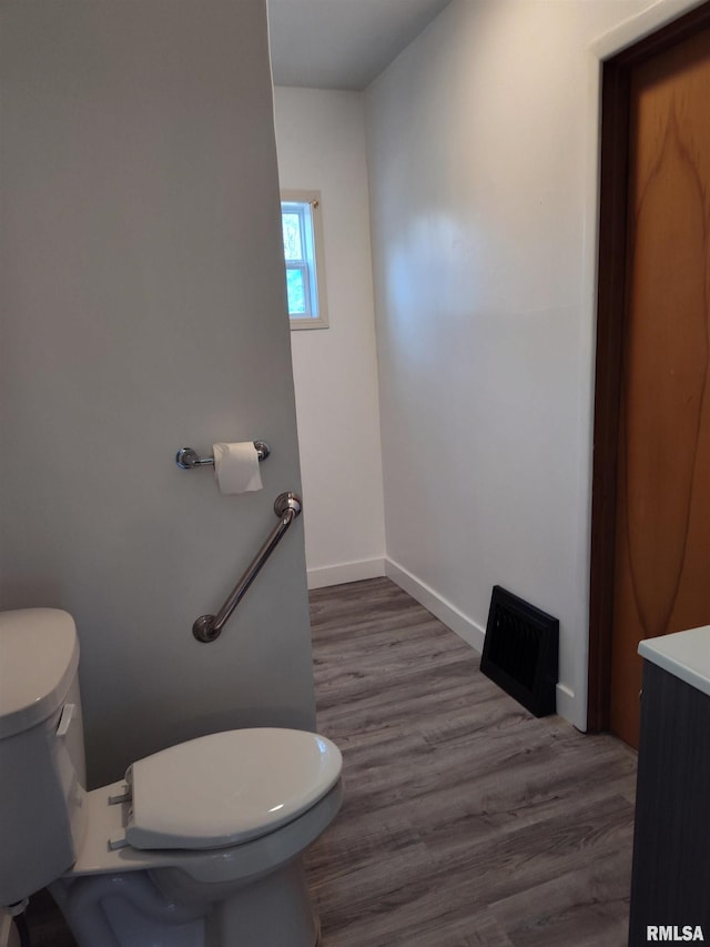 bathroom with baseboards, toilet, wood finished floors, and vanity