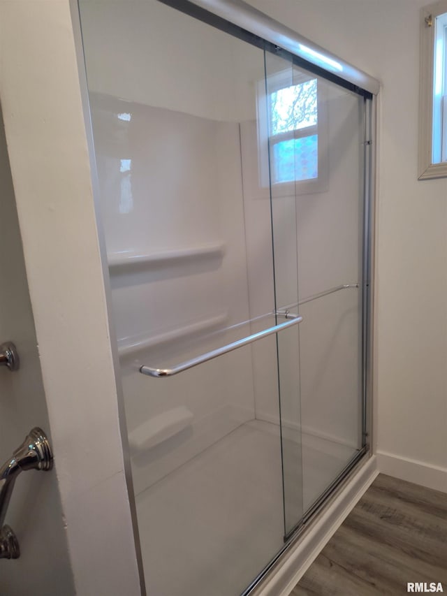 bathroom with wood finished floors, a stall shower, and baseboards