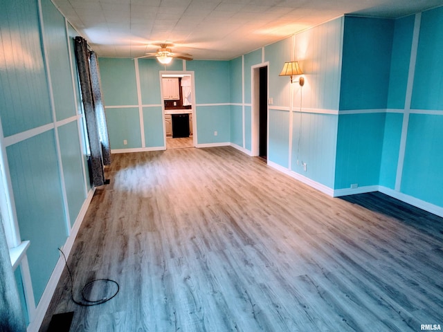 empty room with baseboards, wood finished floors, and a ceiling fan