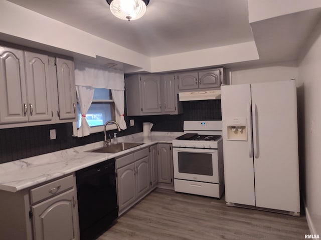 kitchen with white appliances, wood finished floors, gray cabinets, a sink, and under cabinet range hood