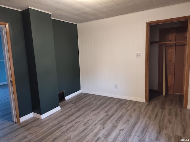 unfurnished bedroom featuring visible vents, wood finished floors, a closet, crown molding, and baseboards