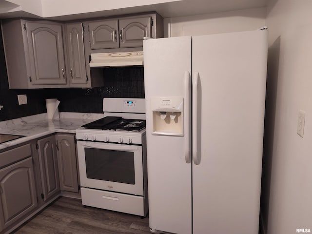 kitchen with under cabinet range hood, dark wood-style floors, white appliances, and gray cabinetry