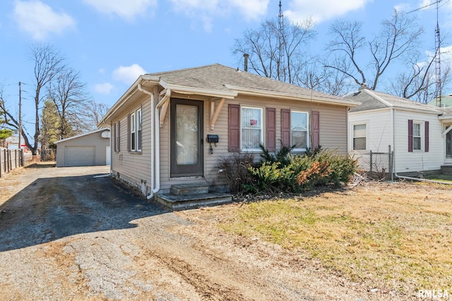 bungalow-style home with fence, driveway, entry steps, an outdoor structure, and a garage