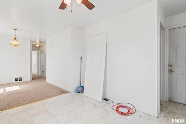 spare room with light carpet, visible vents, baseboards, and a ceiling fan