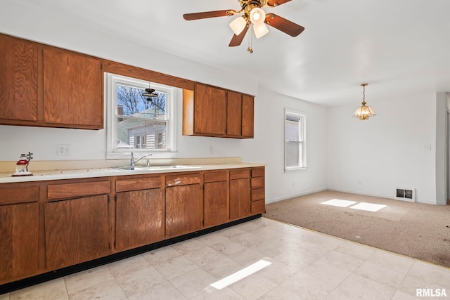 kitchen with light countertops, brown cabinets, visible vents, and a sink