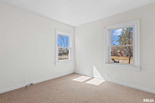 spare room with carpet, baseboards, and a wealth of natural light