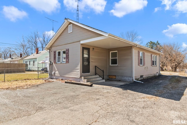 bungalow-style house with entry steps, driveway, and fence