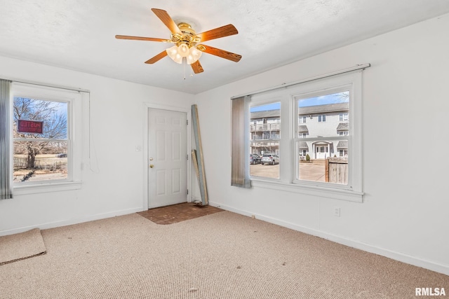 carpeted empty room featuring baseboards and ceiling fan