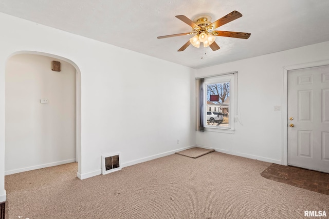 unfurnished room with carpet, baseboards, a ceiling fan, visible vents, and arched walkways