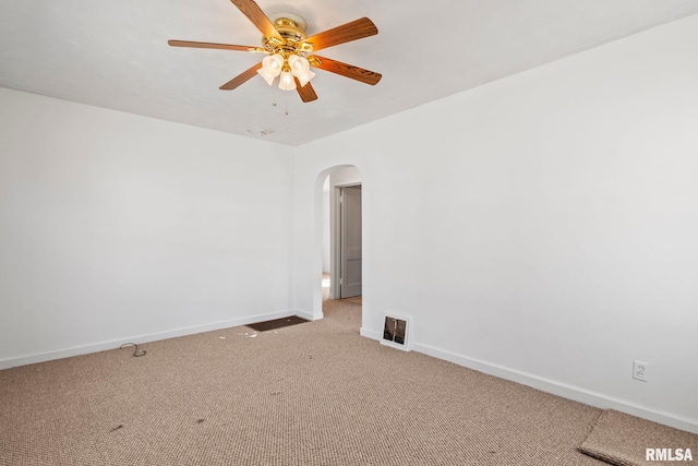 empty room featuring visible vents, ceiling fan, baseboards, light carpet, and arched walkways