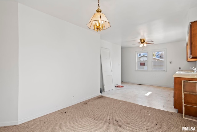 unfurnished dining area with light carpet, ceiling fan with notable chandelier, baseboards, and a sink