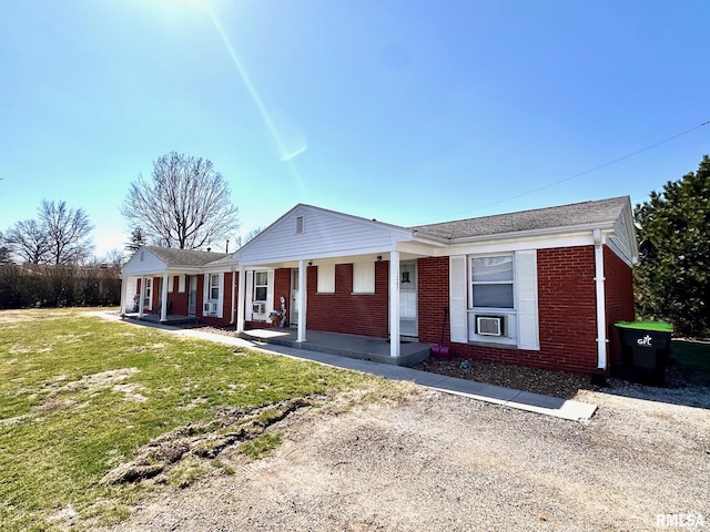 ranch-style home with a front yard, a porch, and brick siding