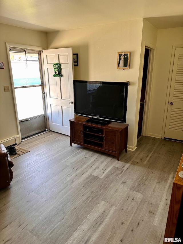 living area featuring baseboard heating, light wood-style flooring, and baseboards