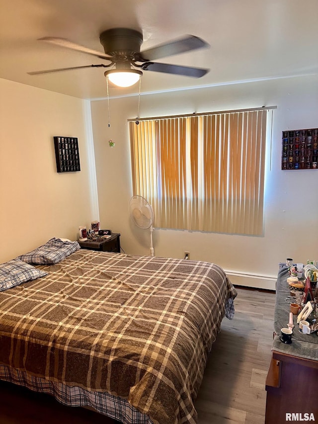 bedroom with wood finished floors, a baseboard radiator, and ceiling fan