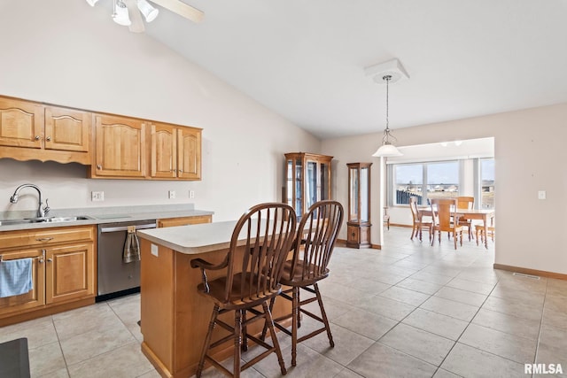 kitchen with stainless steel dishwasher, light countertops, light tile patterned floors, and a sink