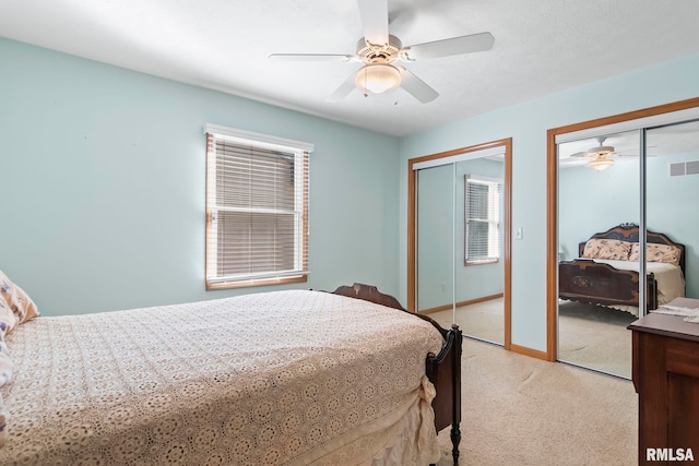 bedroom with visible vents, multiple closets, light carpet, a ceiling fan, and baseboards