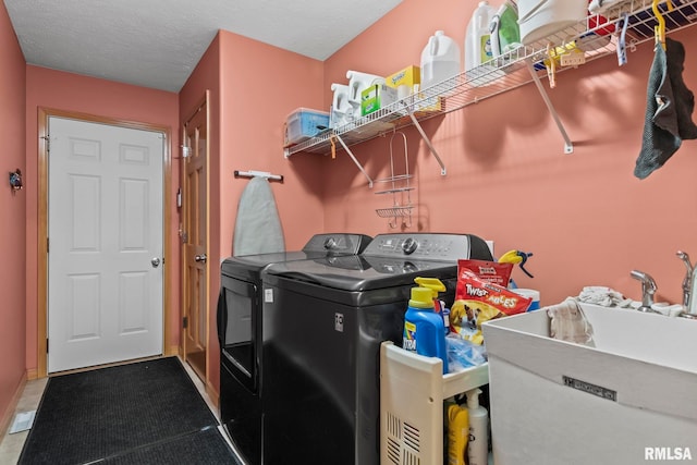 clothes washing area featuring laundry area, a sink, a textured ceiling, and separate washer and dryer