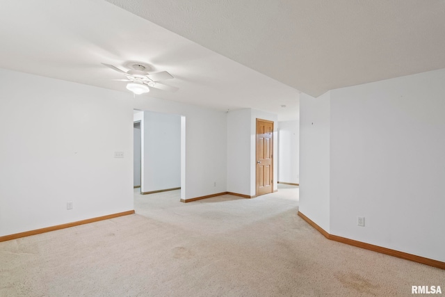 unfurnished room featuring light colored carpet, baseboards, and ceiling fan