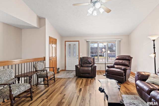 living area with lofted ceiling, baseboards, light wood-type flooring, and ceiling fan