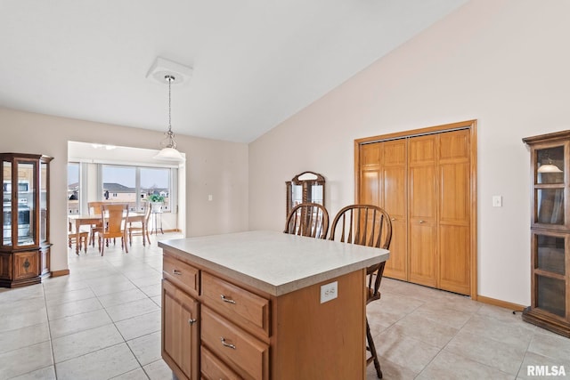 kitchen featuring a kitchen bar, a kitchen island, light tile patterned flooring, light countertops, and vaulted ceiling