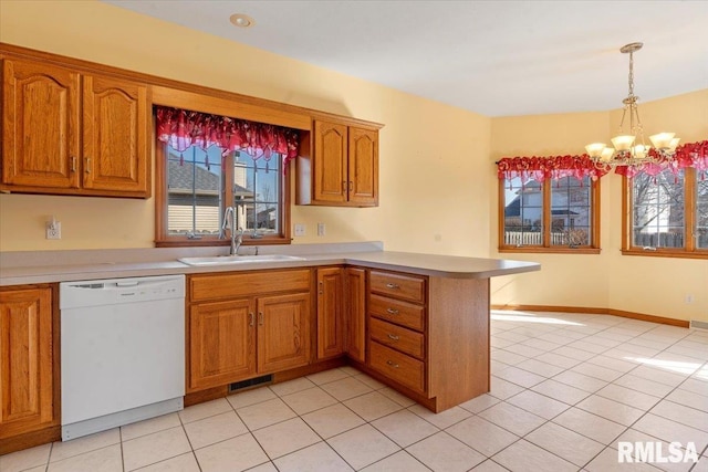 kitchen featuring visible vents, a sink, a peninsula, dishwasher, and a chandelier