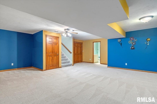 interior space with carpet flooring, baseboards, ceiling fan, and stairs