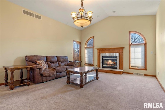 carpeted living area with a glass covered fireplace, vaulted ceiling, baseboards, and visible vents