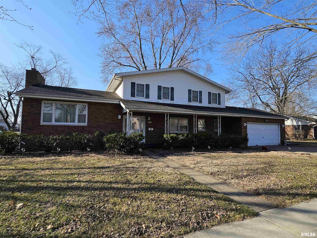 traditional home featuring brick siding, a front yard, a chimney, a garage, and driveway