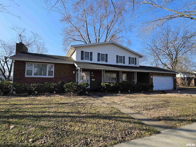 traditional home featuring brick siding, a front yard, a chimney, a garage, and driveway