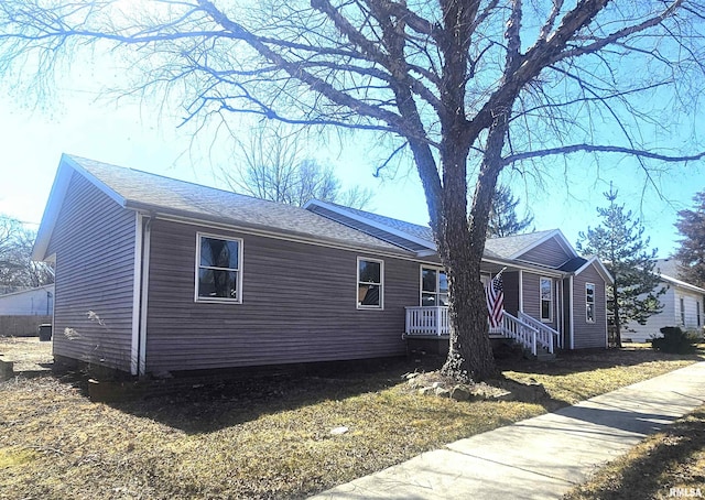 single story home with a porch and a shingled roof