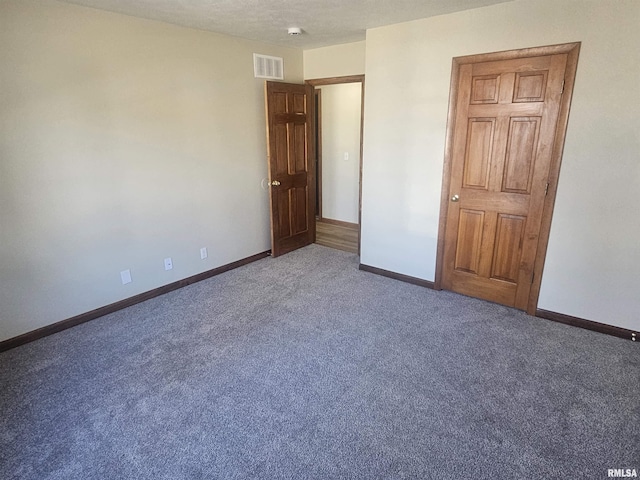 unfurnished bedroom featuring visible vents, carpet floors, a textured ceiling, and baseboards