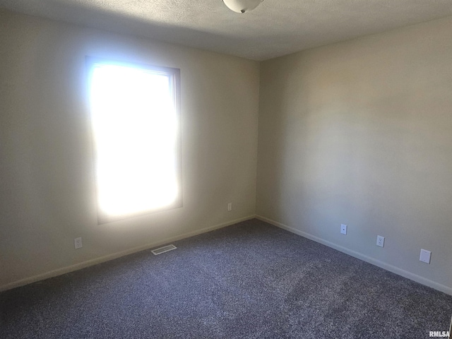 carpeted empty room featuring visible vents, baseboards, and a textured ceiling