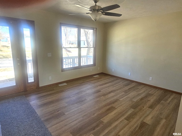 empty room with visible vents, a textured ceiling, ceiling fan, and wood finished floors