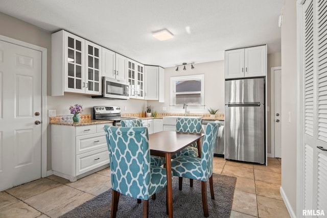 kitchen featuring light tile patterned floors, white cabinets, appliances with stainless steel finishes, and glass insert cabinets