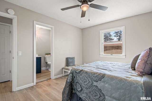 bedroom featuring light wood-style flooring, a ceiling fan, baseboards, and ensuite bathroom