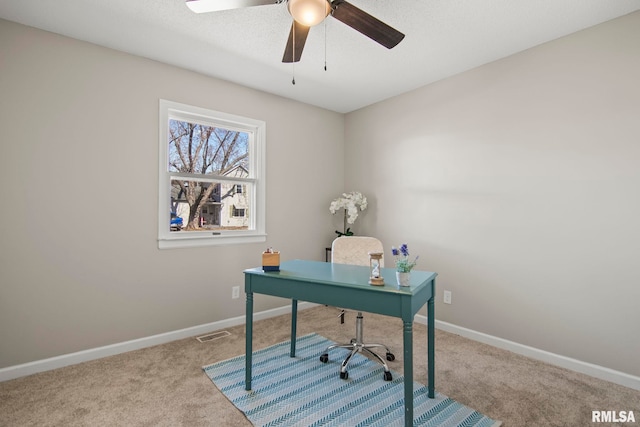 carpeted home office featuring visible vents, baseboards, and ceiling fan