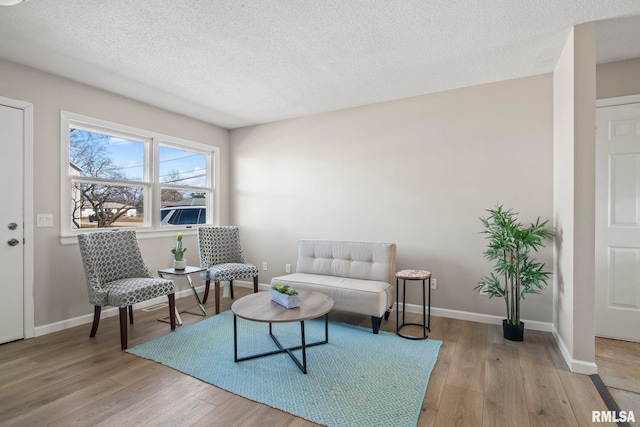 sitting room featuring wood finished floors, baseboards, and a textured ceiling