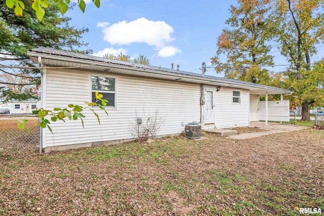 back of house featuring entry steps, fence, central AC, and metal roof