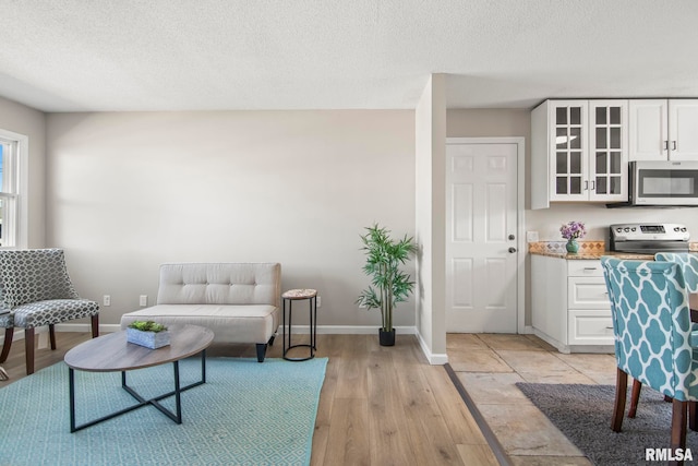 living room with light wood-style floors, baseboards, and a textured ceiling