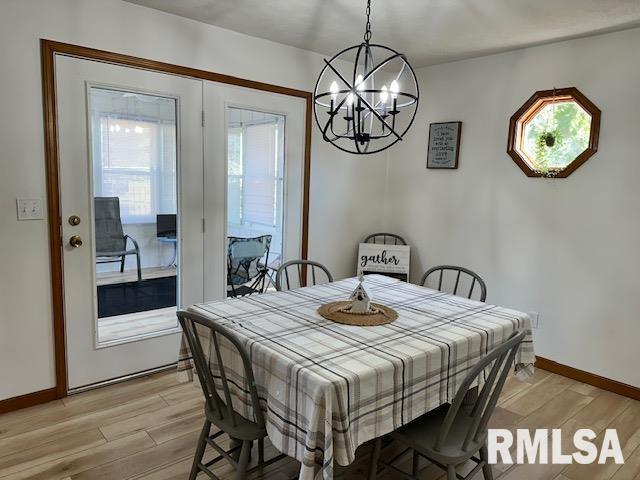 dining space with light wood finished floors, a notable chandelier, and baseboards