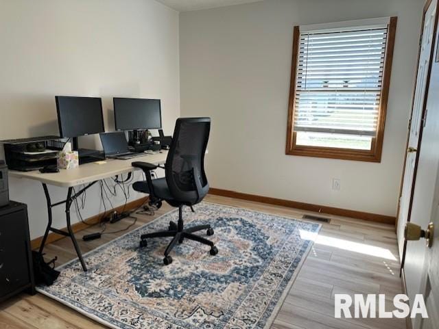 office space with light wood finished floors, visible vents, and baseboards