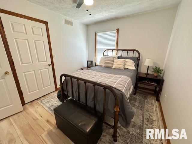 bedroom with visible vents, a textured ceiling, light wood-style floors, and a ceiling fan