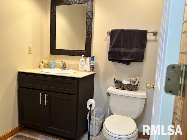 bathroom featuring baseboards, toilet, and vanity