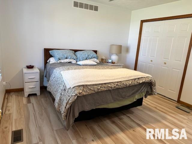 bedroom featuring a closet, visible vents, and light wood finished floors