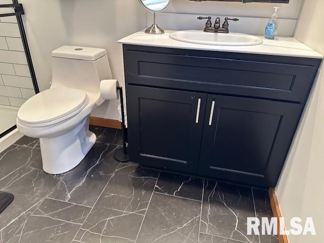 bathroom with toilet, marble finish floor, and vanity