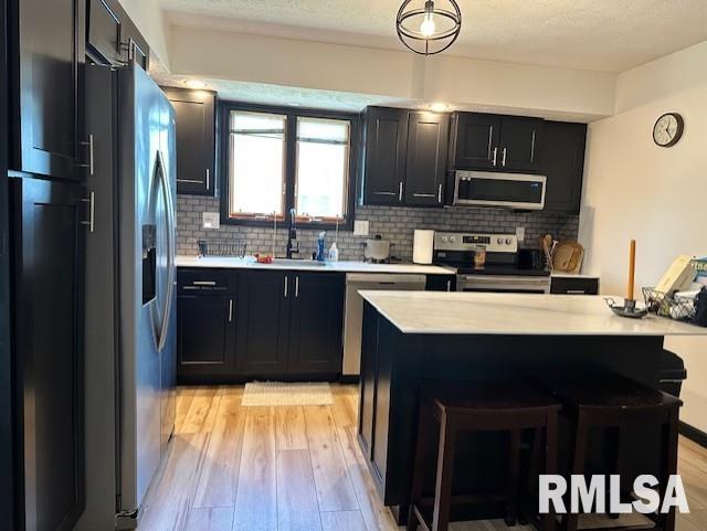 kitchen featuring dark cabinets, stainless steel appliances, light countertops, and a sink