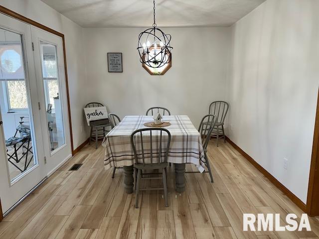 dining room with a chandelier, light wood finished floors, and baseboards